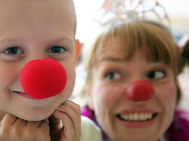 boy with red nose smiling and female clown behind him